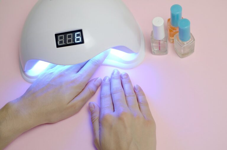 Hands of young woman at manicure procedure close up on pastel pink background